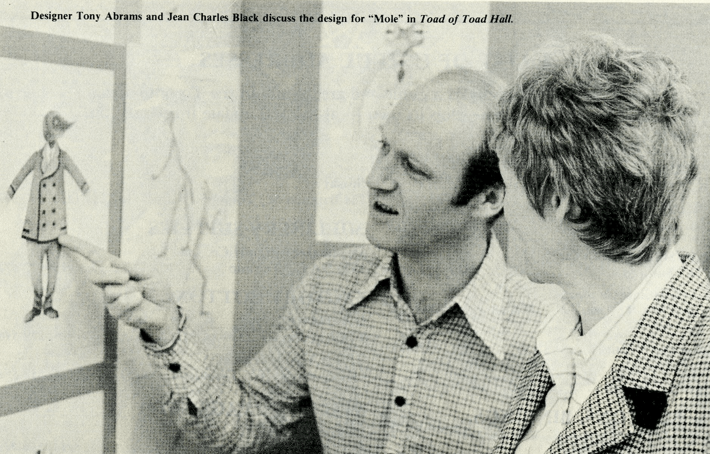 Two people look at a drawing of a mole in a fancy suit.